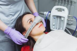 Dentist administering inhalation sedation to a patient during dental treatment.